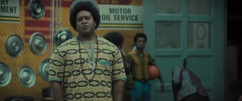 Movie still from “The Many Saints of Newark” (2021), directed by Alan Taylor – A man in a yellow shirt is standing next to another man in a yellow shirt; Medium shot, Low angle