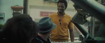 Movie still from “The Many Saints of Newark” (2021), directed by Alan Taylor – A man in a yellow shirt is smiling; Medium shot, Over the shoulder angle