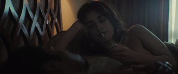 Movie still from “The Many Saints of Newark” (2021), directed by Alan Taylor – A woman smoking a cigarette while sitting on a bed; Close Up shot, High angle