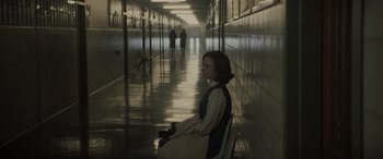 Movie still from “The Many Saints of Newark” (2021), directed by Alan Taylor – A woman sitting on a chair in a hallway; Wide shot, High angle