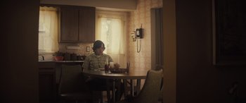 A man sitting at a table with a bottle of beer