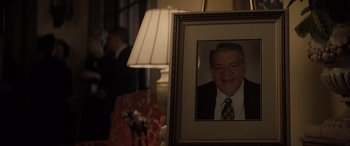 Movie still from “The Many Saints of Newark” (2021), directed by Alan Taylor – A picture of an older man in a suit and tie in front of a lamp; Close Up shot, Over the shoulder angle