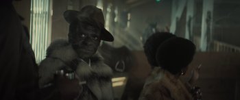 Movie still from “The Many Saints of Newark” (2021), directed by Alan Taylor – A man in a fur coat and hat on a train; Close Up shot, Over the shoulder angle