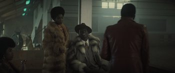 Movie still from “The Many Saints of Newark” (2021), directed by Alan Taylor – A man in a fur coat sitting next to two women; Medium shot, Over the shoulder angle