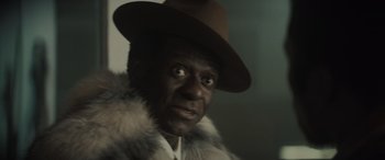 Movie still from “The Many Saints of Newark” (2021), directed by Alan Taylor – A person wearing a hat and a fur coat; Close Up shot, Over the shoulder angle