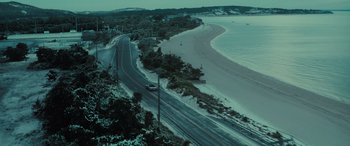 Movie still from “The Many Saints of Newark” (2021), directed by Alan Taylor – An aerial view of a road near the ocean; Extreme Wide shot, High angle