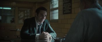 Movie still from “The Many Saints of Newark” (2021), directed by Alan Taylor – A man sitting at a table in front of a window; Medium shot, Over the shoulder angle