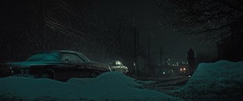 Movie still from “The Many Saints of Newark” (2021), directed by Alan Taylor – A car is parked in the snow at night; Extreme Wide shot, Low angle