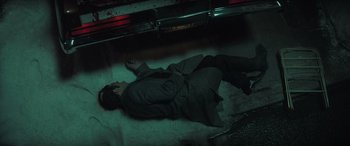 Movie still from “The Many Saints of Newark” (2021), directed by Alan Taylor – A man is laying on the ground in the dark; Wide shot, Overhead angle