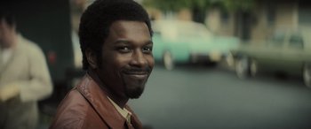 Movie still from “The Many Saints of Newark” (2021), directed by Alan Taylor – A person smiling for a picture; Close Up shot, Over the shoulder angle