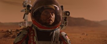Movie still from “The Martian” (2015), directed by Ridley Scott – A man wearing a space suit and a helmet; Close Up shot, Overhead angle