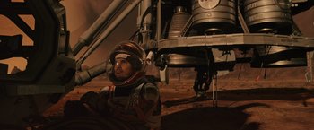 Movie still from “The Martian” (2015), directed by Ridley Scott – A man in a space suit standing next to an object on the surface of mars; Wide shot, High angle
