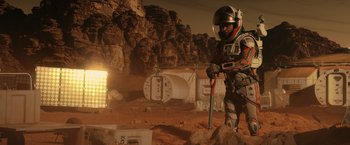 Movie still from “The Martian” (2015), directed by Ridley Scott – A man in a space suit is standing on a dirt field; Wide shot, Low angle
