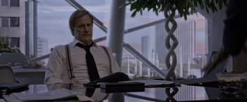 Movie still from “The Martian” (2015), directed by Ridley Scott – A man sitting at a table in front of a city skyline; Medium shot, Over the shoulder angle