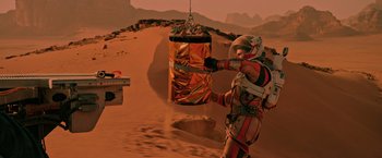 Movie still from “The Martian” (2015), directed by Ridley Scott – A man in a spacesuit is holding a metal object; Extreme Wide shot, High angle