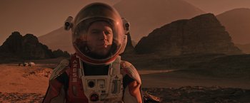 Movie still from “The Martian” (2015), directed by Ridley Scott – A man wearing a space suit and a helmet; Close Up shot, Low angle