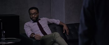 Movie still from “The Martian” (2015), directed by Ridley Scott – A man sitting on top of a black leather couch; Medium shot, High angle