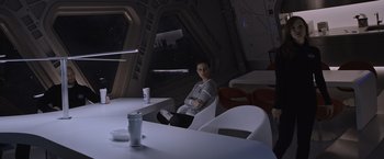 Movie still from “The Martian” (2015), directed by Ridley Scott – A woman sitting at a table in front of a space ship; Wide shot, Over the shoulder angle