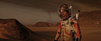 Movie still from “The Martian” (2015), directed by Ridley Scott – A man in a spacesuit standing in front of a desert landscape; Medium shot, Low angle