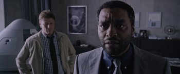 Movie still from “The Martian” (2015), directed by Ridley Scott – A man in a suit and tie standing next to another man in a suit and tie; Close Up shot, Over the shoulder angle