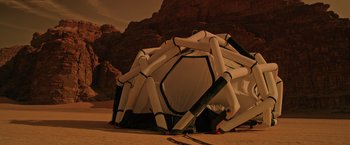 Movie still from “The Martian” (2015), directed by Ridley Scott – An inflatable tent is in the sand near a rocky mountain side; Extreme Wide shot, Low angle