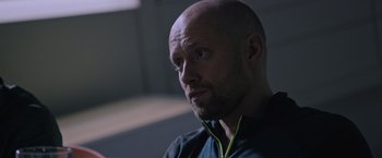 Movie still from “The Martian” (2015), directed by Ridley Scott – A bald man wearing a blue shirt is listening to music; Close Up shot, Low angle