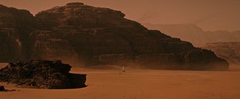 Movie still from “The Martian” (2015), directed by Ridley Scott – A person standing in the sand in front of a mountain; Extreme Wide shot, Low angle