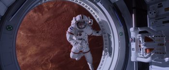 Movie still from “The Martian” (2015), directed by Ridley Scott – A person in a spacesuit standing inside of a space station; Wide shot, Overhead angle