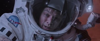 Movie still from “The Martian” (2015), directed by Ridley Scott – A man in a spacesuit looking into the camera; Close Up shot, Overhead angle