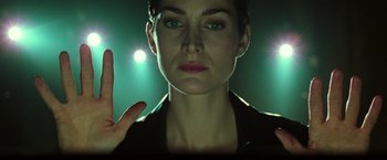 Movie still from “The Matrix” (1999), directed by Lana Wachowski – A woman's face in front of lights; Close Up shot, Low angle