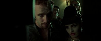 Movie still from “The Matrix” (1999), directed by Lana Wachowski – A group of people standing next to each other in a room; Close Up shot, Low angle