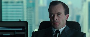 Movie still from “The Matrix” (1999), directed by Lana Wachowski – A person wearing a suit and tie; Close Up shot, Over the shoulder angle