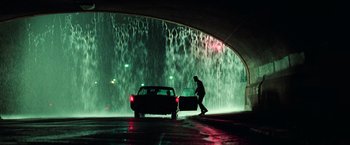 Movie still from “The Matrix” (1999), directed by Lana Wachowski – A man standing next to a car in a tunnel; Wide shot, Low angle