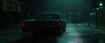 Movie still from “The Matrix” (1999), directed by Lana Wachowski – A car driving down a wet street in the rain; Wide shot, Low angle