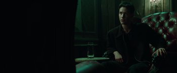Movie still from “The Matrix” (1999), directed by Lana Wachowski – A man sitting at a table with a glass of water; Medium shot, Over the shoulder angle