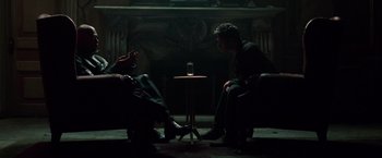Movie still from “The Matrix” (1999), directed by Lana Wachowski – Two people sitting in front of a table with a drink on top of it; Medium shot, Over the shoulder angle