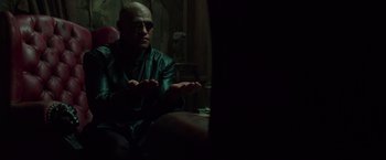 Movie still from “The Matrix” (1999), directed by Lana Wachowski – A man sitting in front of a mirror in a dark room; Medium shot, High angle