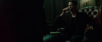 Movie still from “The Matrix” (1999), directed by Lana Wachowski – A man sitting at a table drinking a glass of wine; Medium shot, Over the shoulder angle