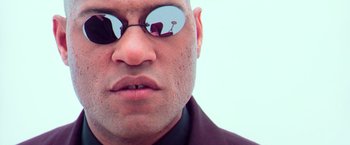 Movie still from “The Matrix” (1999), directed by Lana Wachowski – A person wearing sunglasses; Extreme Close Up shot, Low angle