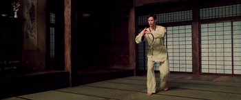Movie still from “The Matrix” (1999), directed by Lana Wachowski – A man in a karate outfit is doing an exercise; Medium shot, High angle