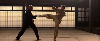 Movie still from “The Matrix” (1999), directed by Lana Wachowski – Two men are practicing martial arts in an indoor setting; Wide shot, Low angle