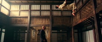 Movie still from “The Matrix” (1999), directed by Lana Wachowski – A man standing in front of a person jumping in the air; Wide shot, Low angle