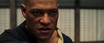 Movie still from “The Matrix” (1999), directed by Lana Wachowski – A man's face in a black shirt; Close Up shot, Over the shoulder angle