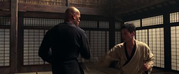 Movie still from “The Matrix” (1999), directed by Lana Wachowski – Two men are practicing martial arts in a dojo; Medium shot, Over the shoulder angle