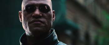 Movie still from “The Matrix” (1999), directed by Lana Wachowski – A person wearing sunglasses; Close Up shot, Low angle