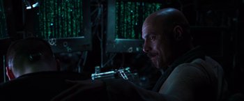 Movie still from “The Matrix” (1999), directed by Lana Wachowski – A man with a bald head is in a room with green lights; Close Up shot, Low angle