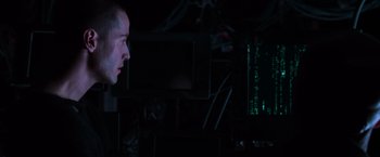 Movie still from “The Matrix” (1999), directed by Lana Wachowski – A man in a dark room looking at a computer screen; Close Up shot, Over the shoulder angle