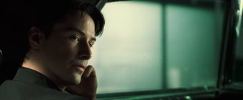 Movie still from “The Matrix” (1999), directed by Lana Wachowski – A person sitting in a car; Close Up shot, Over the shoulder angle