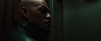 Movie still from “The Matrix” (1999), directed by Lana Wachowski – A bald man with sunglasses looking to his left; Close Up shot, Low angle