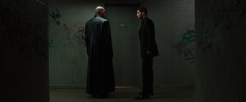 Movie still from “The Matrix” (1999), directed by Lana Wachowski – Two men standing in front of each other in front of a door; Medium shot, Low angle